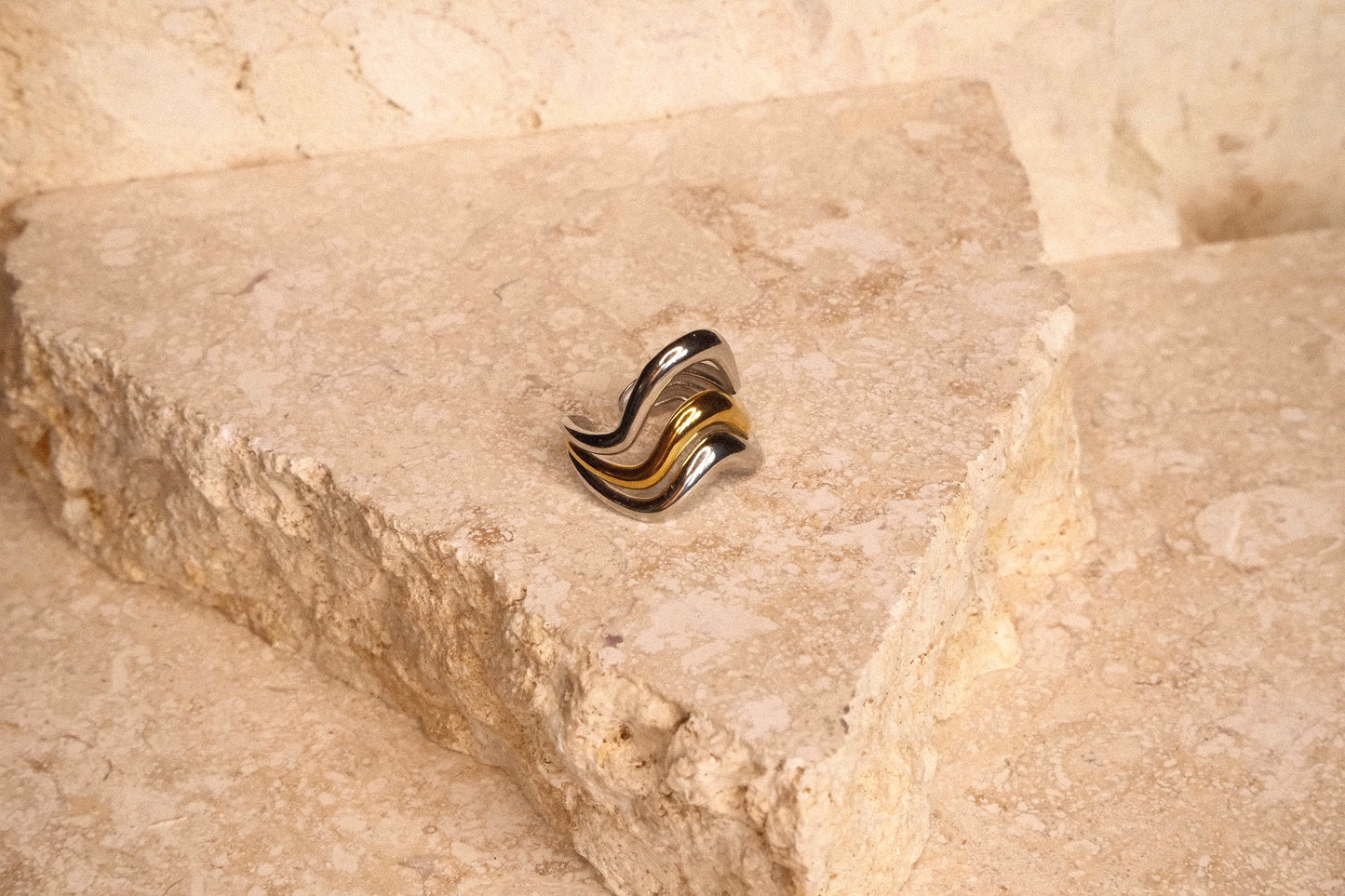 Gold and silver ring on a textured stone surface