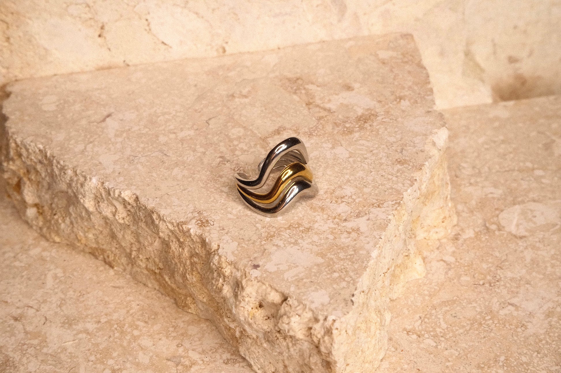 Gold and silver ring on a textured stone surface