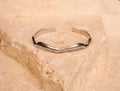 Silver bracelet on a textured beige stone surface
