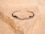 Silver bracelet on a textured beige stone surface
