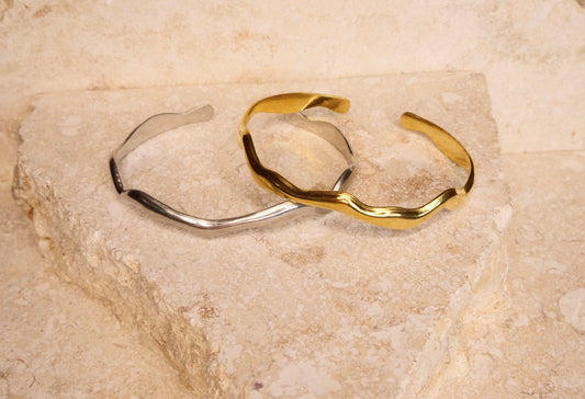 Two gold and silver bangles on a textured stone surface