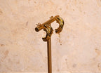 Gold earrings on stand against a beige marble background