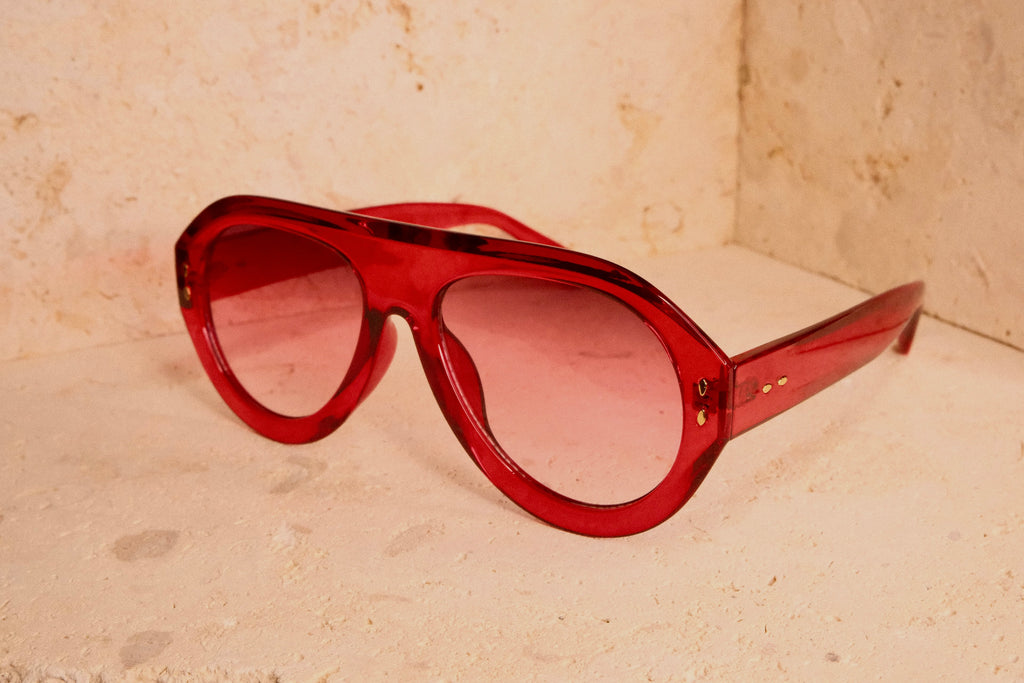 Red sunglasses on a beige surface