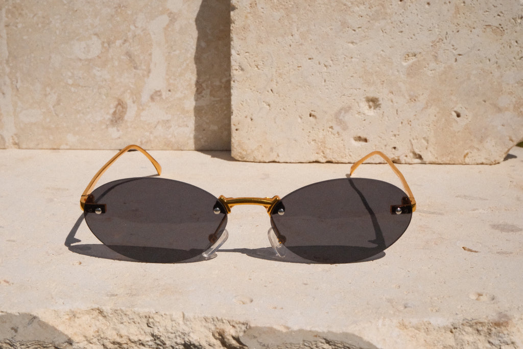 Sunglasses with gold frame and dark lenses on a stone surface