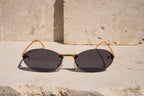 Sunglasses with gold frame and dark lenses on a stone surface