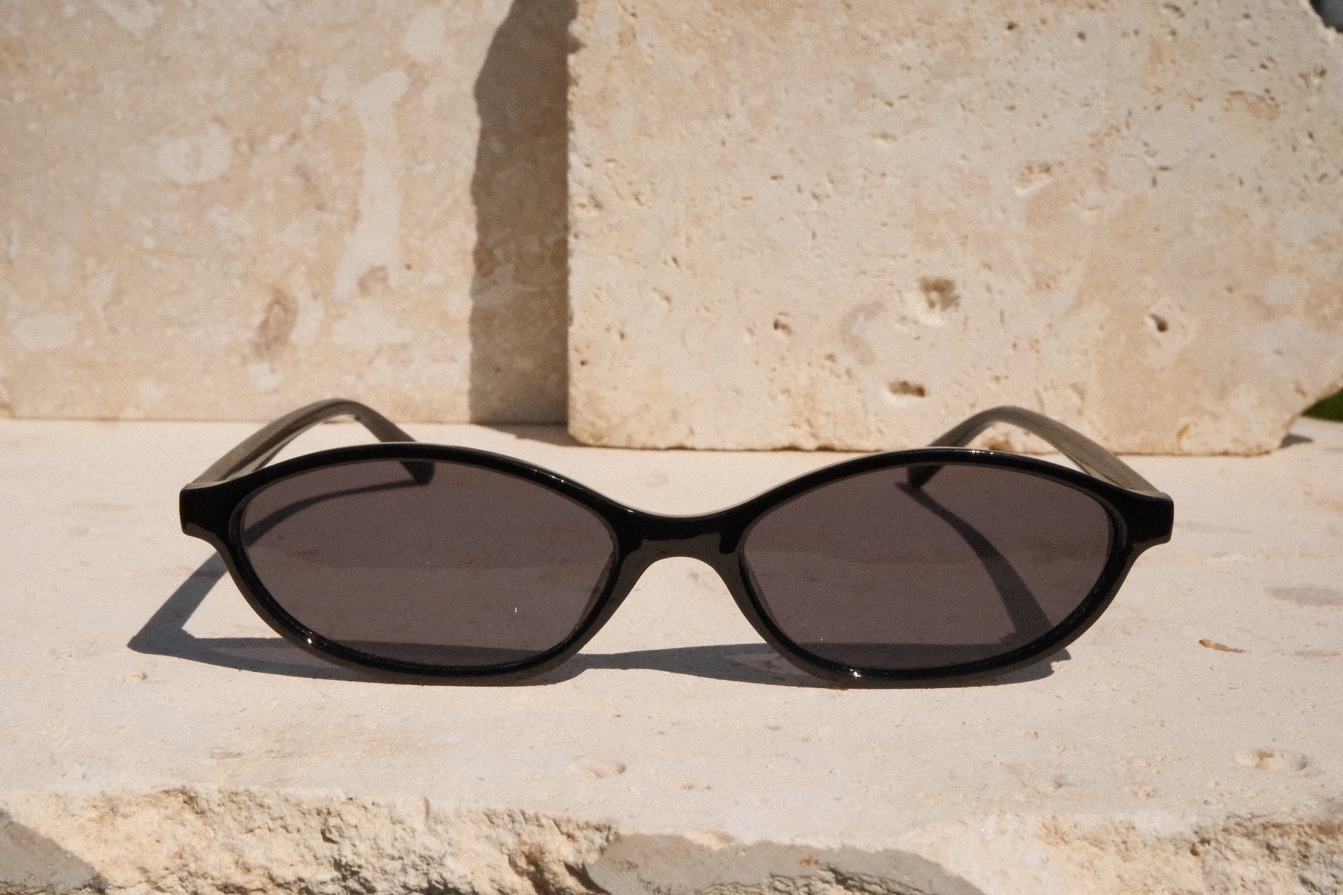 Black sunglasses on a stone surface with a stone wall background