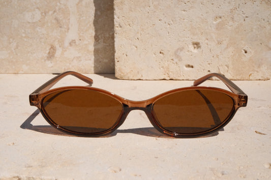 Brown sunglasses on a stone surface with a stone wall background