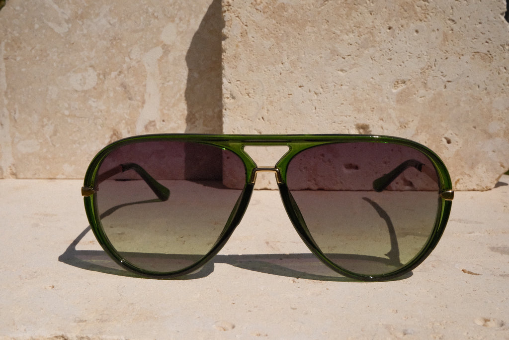 Green sunglasses with dark lenses on a stone surface