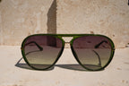 Green sunglasses with dark lenses on a stone surface