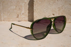 Green sunglasses with gold frame on a stone surface