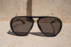 Black aviator sunglasses on a stone surface with a stone wall background