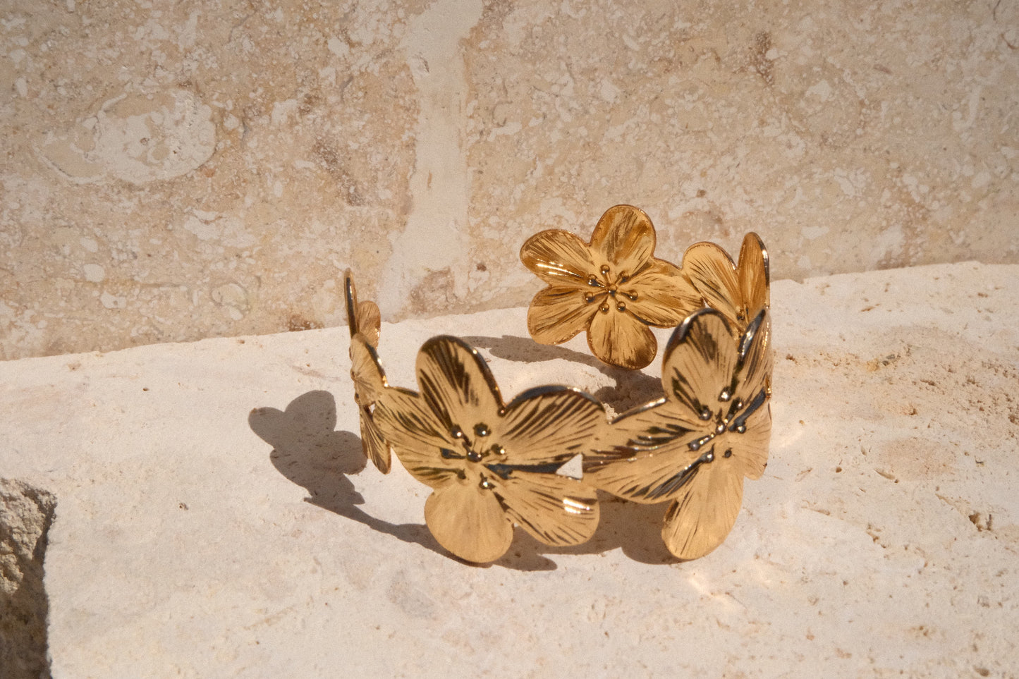 Gold floral bracelet on a textured stone surface