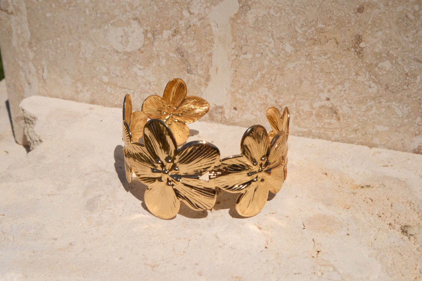 Gold floral bracelet on a textured stone surface