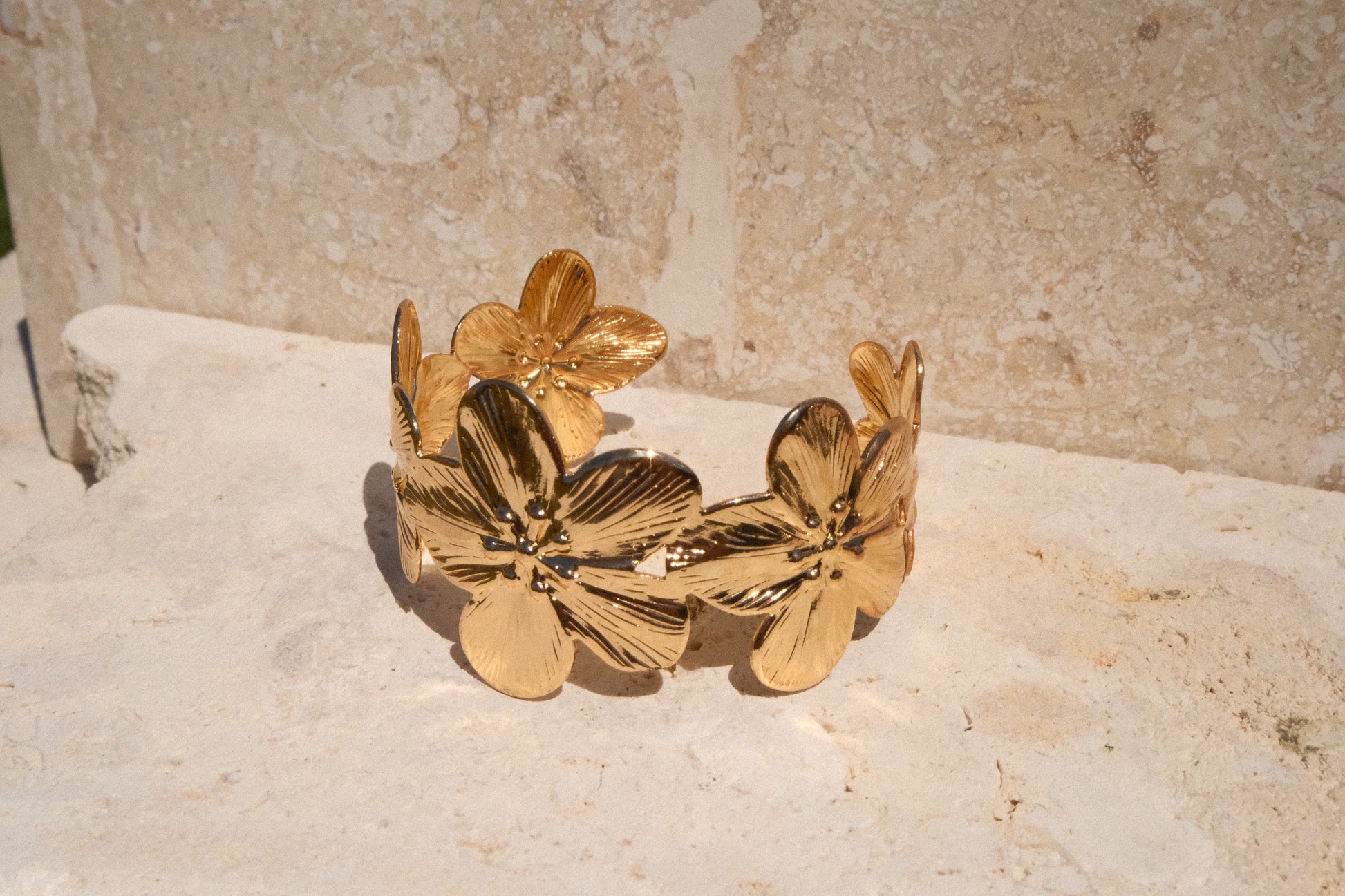 Gold floral bracelet on a textured stone surface