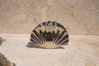 Shell-shaped claw clip on a stone surface with a beige background