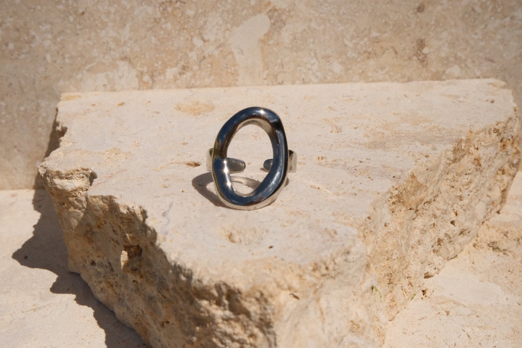 Silver ring with a black stone on a textured beige surface