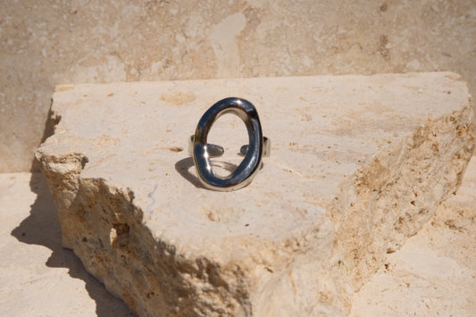 Silver ring with a black stone on a textured beige surface
