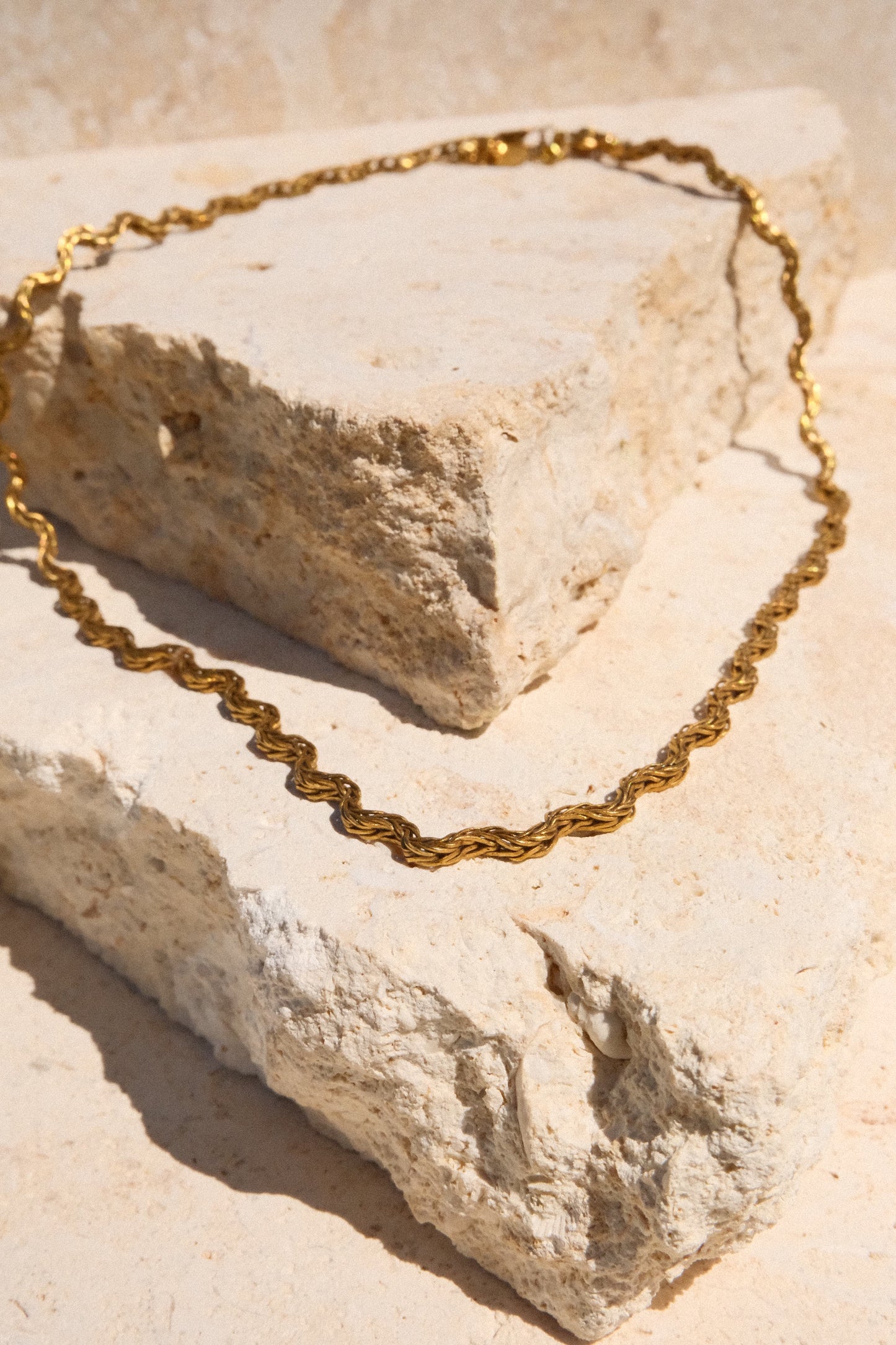 Gold chain necklace on a textured stone surface