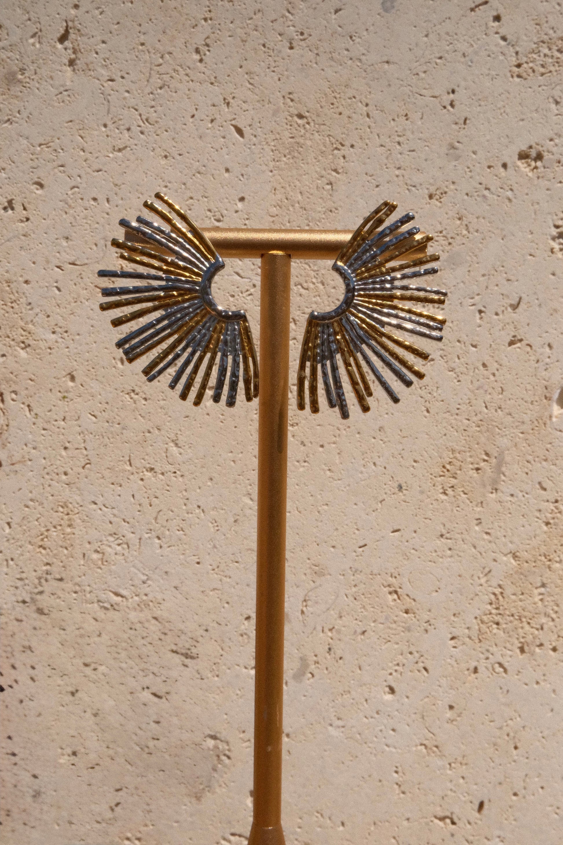 Decorative metal stand with fan-like top on a beige stone background