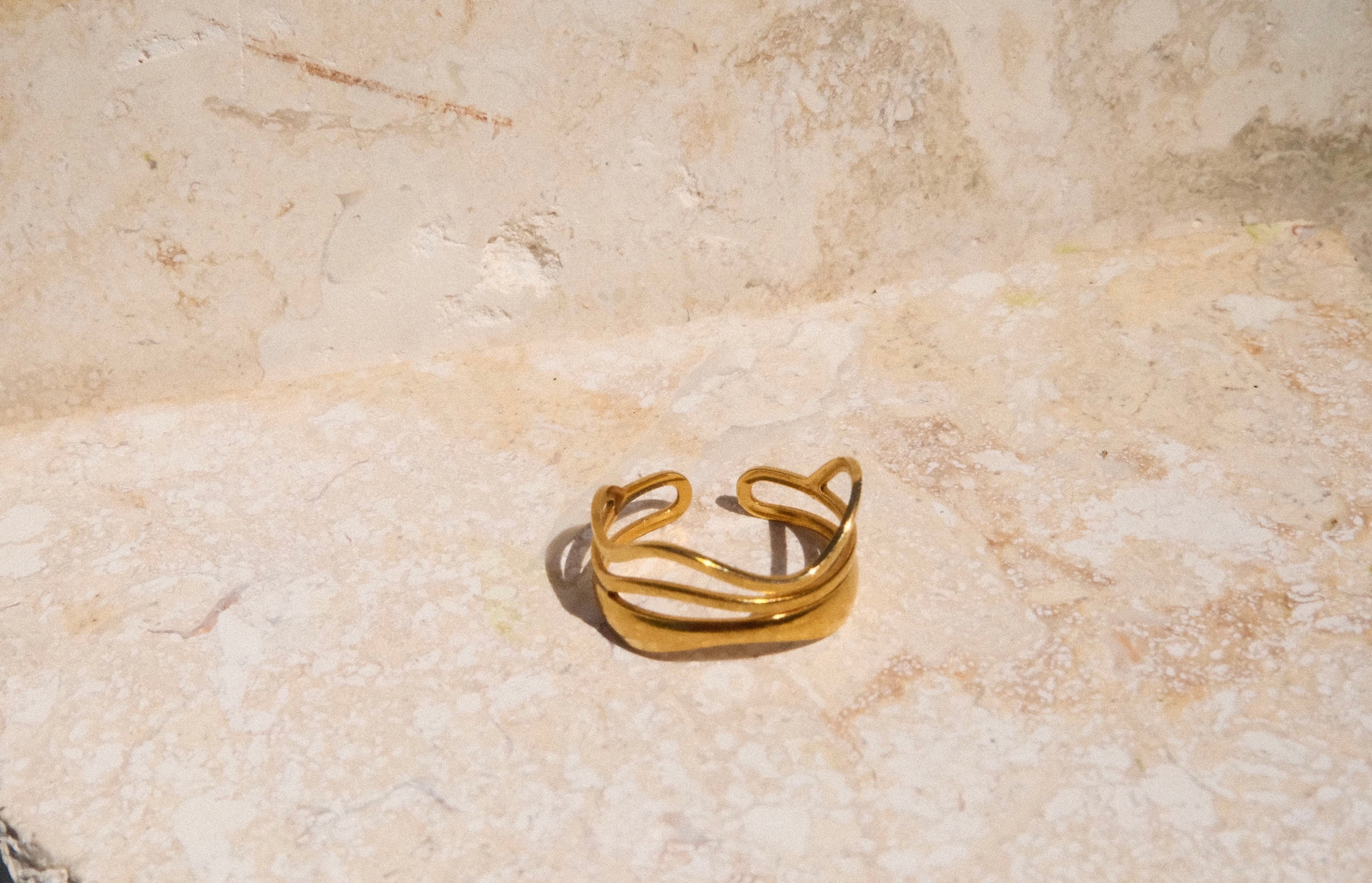 Gold ring on a textured beige surface