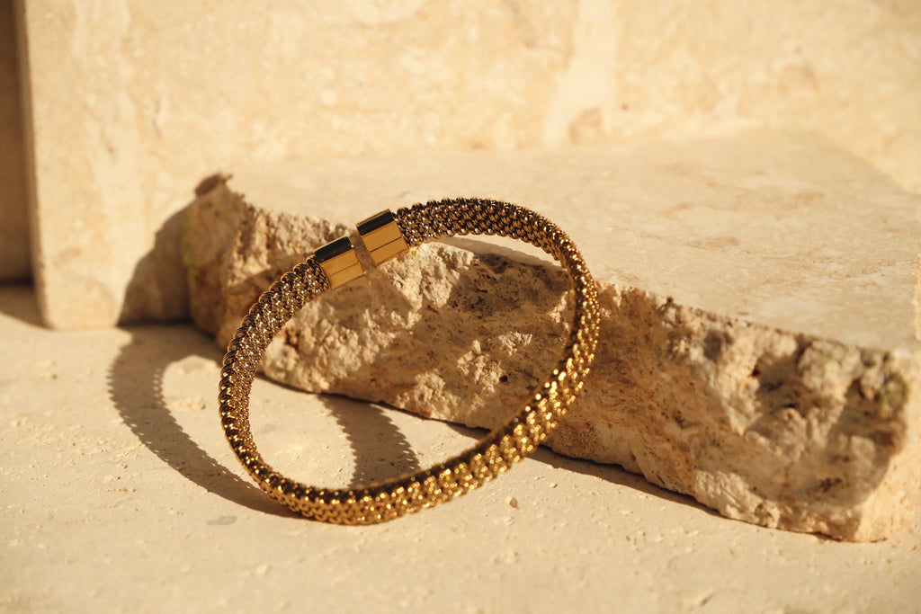 Gold bracelet on a textured stone surface