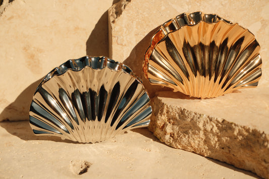 Two shell-shaped claw clips on a textured beige surface