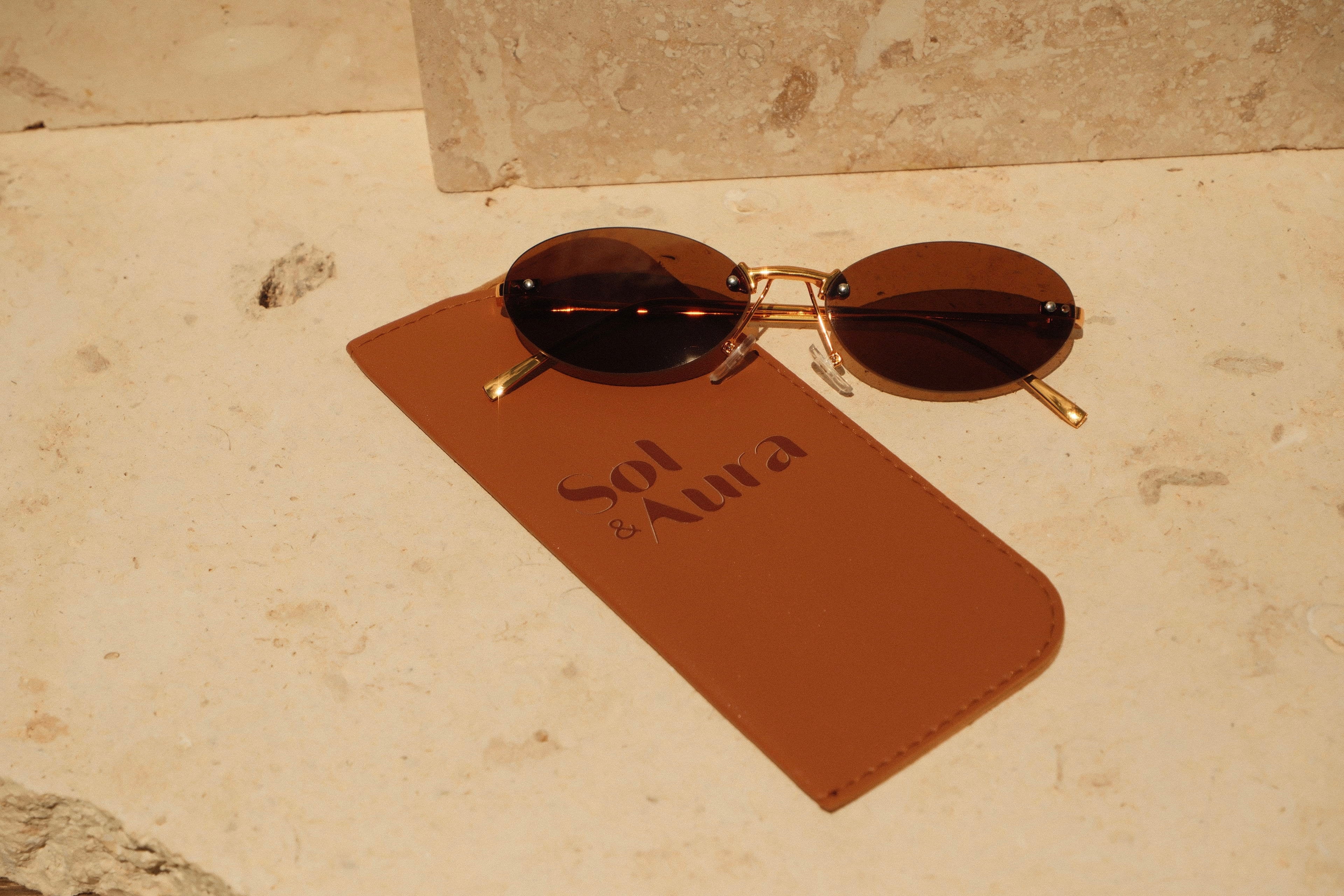 Sunglasses on a brown card with 'Sol Aura' branding on a stone surface