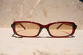 Sol & Aura - Erin Sunglasses. Red sunglasses with light tinted lens sitting on stone surface with three silver dot detailing on either side of lens