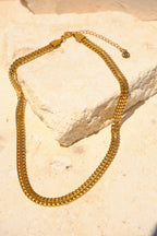 Sol & Aura - Gold chain 'Spiga Necklace' lying on stone surface with S/A logo