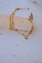 Sol & Aura - Gold anklet with a pendant hanging over a textured stone surface