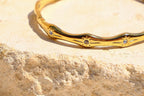 Sol & Aura - Gold bracelet with gemstones on a textured stone surface