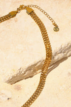 Sol & Aura - Gold chain on natural stone surface with S/A logo
