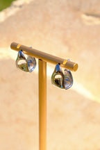Sol & Aura - Gold earring display stand with two silver earrings on a beige background