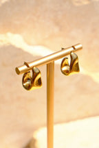 Sol & Aura - Gold earring on a stand with a natual stone background