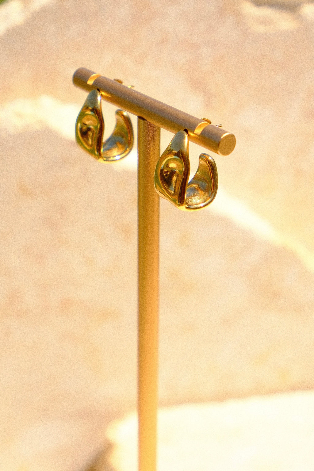 Sol & Aura - Gold earring stand with two gold hoop earrings with a natural stone background