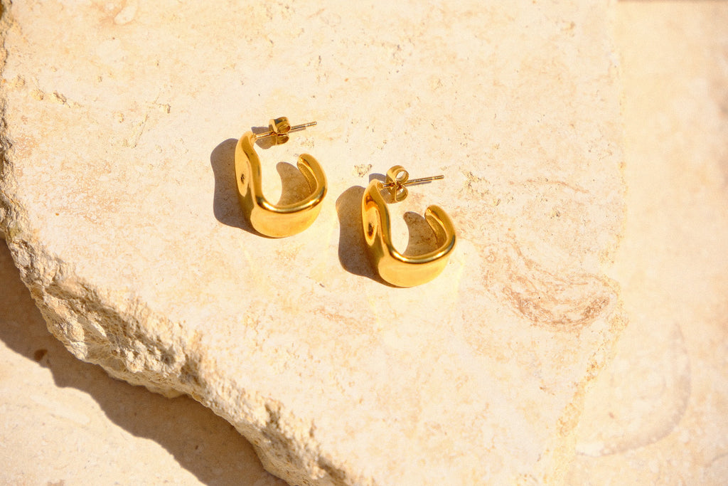 Sol & Aura - Gold hoop earrings on a textured stone surface