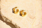 Sol & Aura - Gold hoop earrings on a textured stone surface