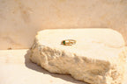 Sol & Aura - Gold ring with a green gemstone on a textured stone surface