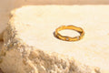Sol & Aura - Gold ring with diamond gemstones on a textured stone surface