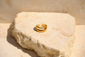 Sol & Aura - Gold two-layer ring on a textured stone surface