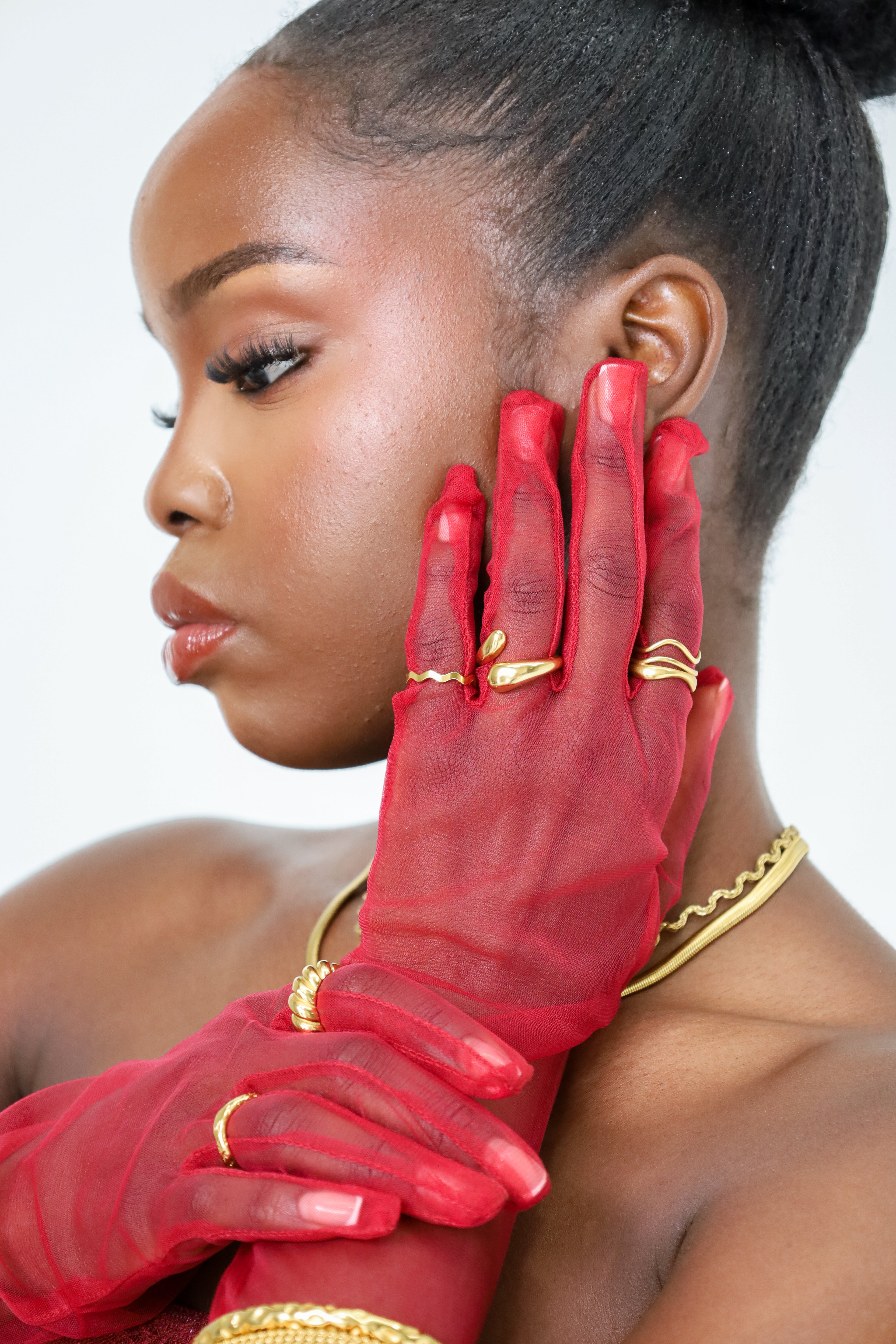 Woman wearing red gloves with gold accents on a white background