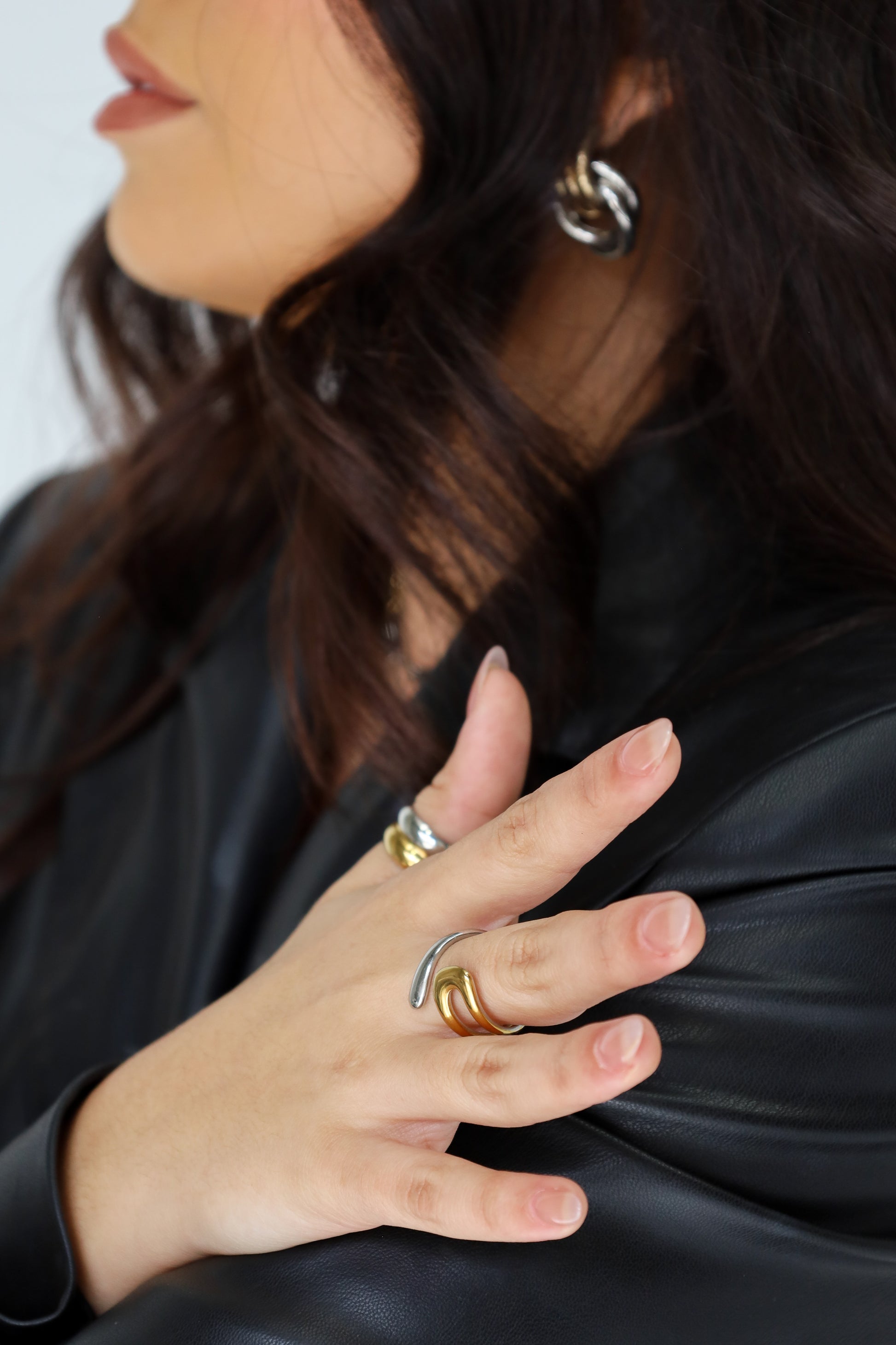 Close-up of a person wearing multiple rings on a plain background