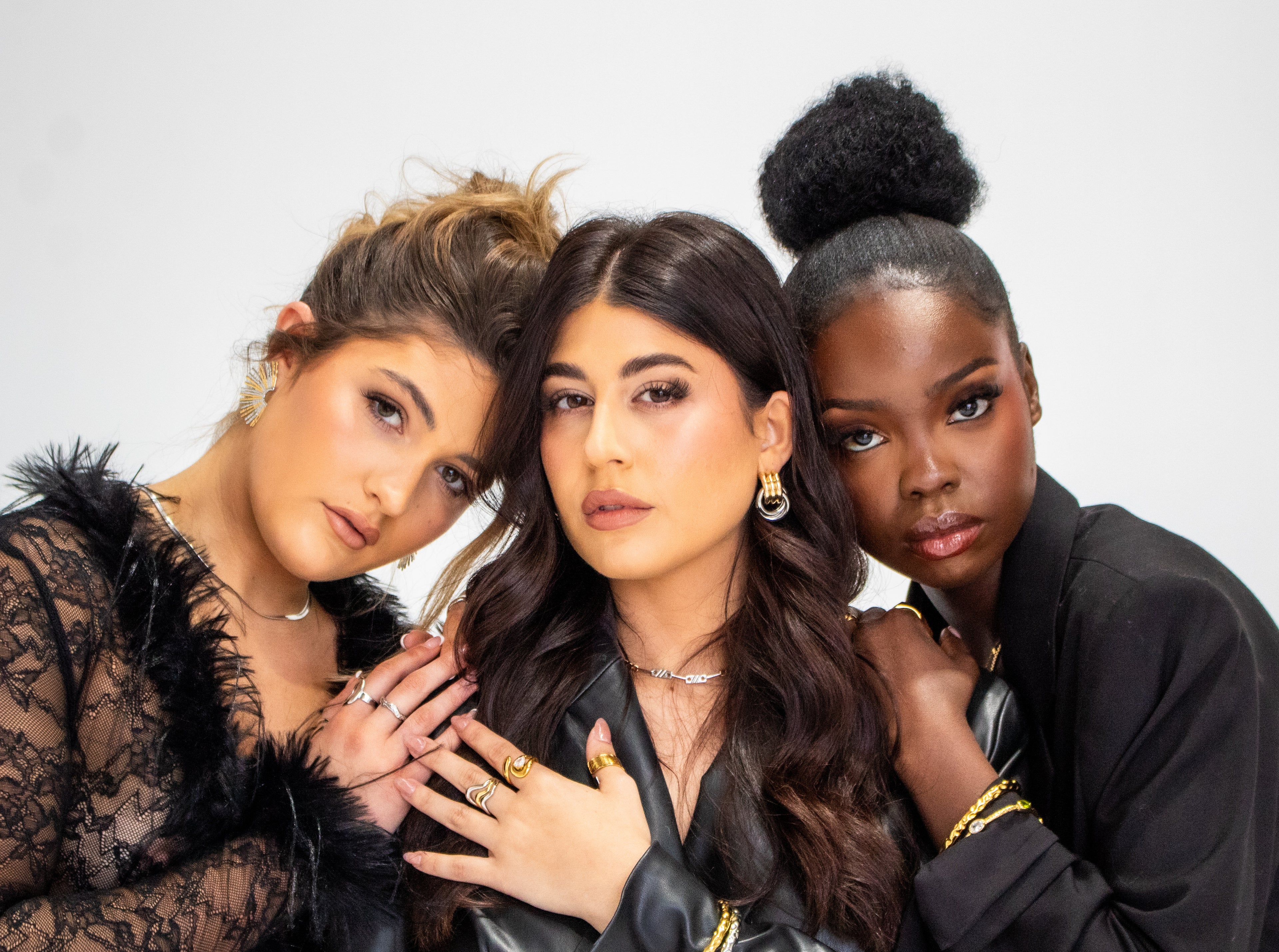 Three women posing together against a white background
