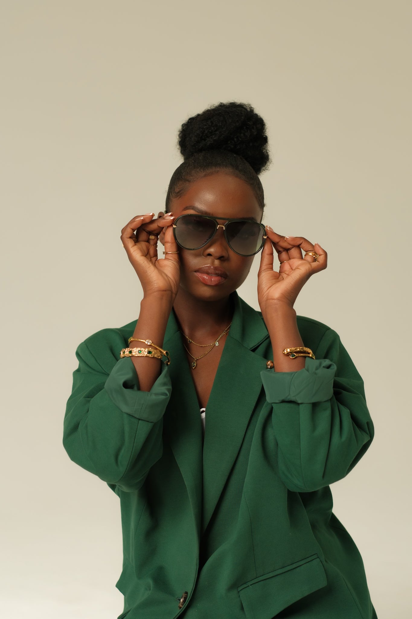 Woman wearing a green outfit and sunglasses against a plain background