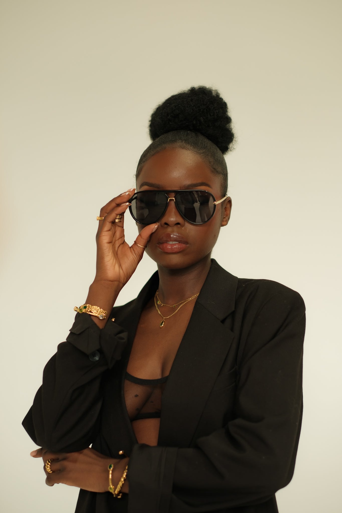 Woman wearing sunglasses and a black outfit against a plain background