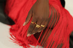 Hand with gold rings on a red fringed fabric background