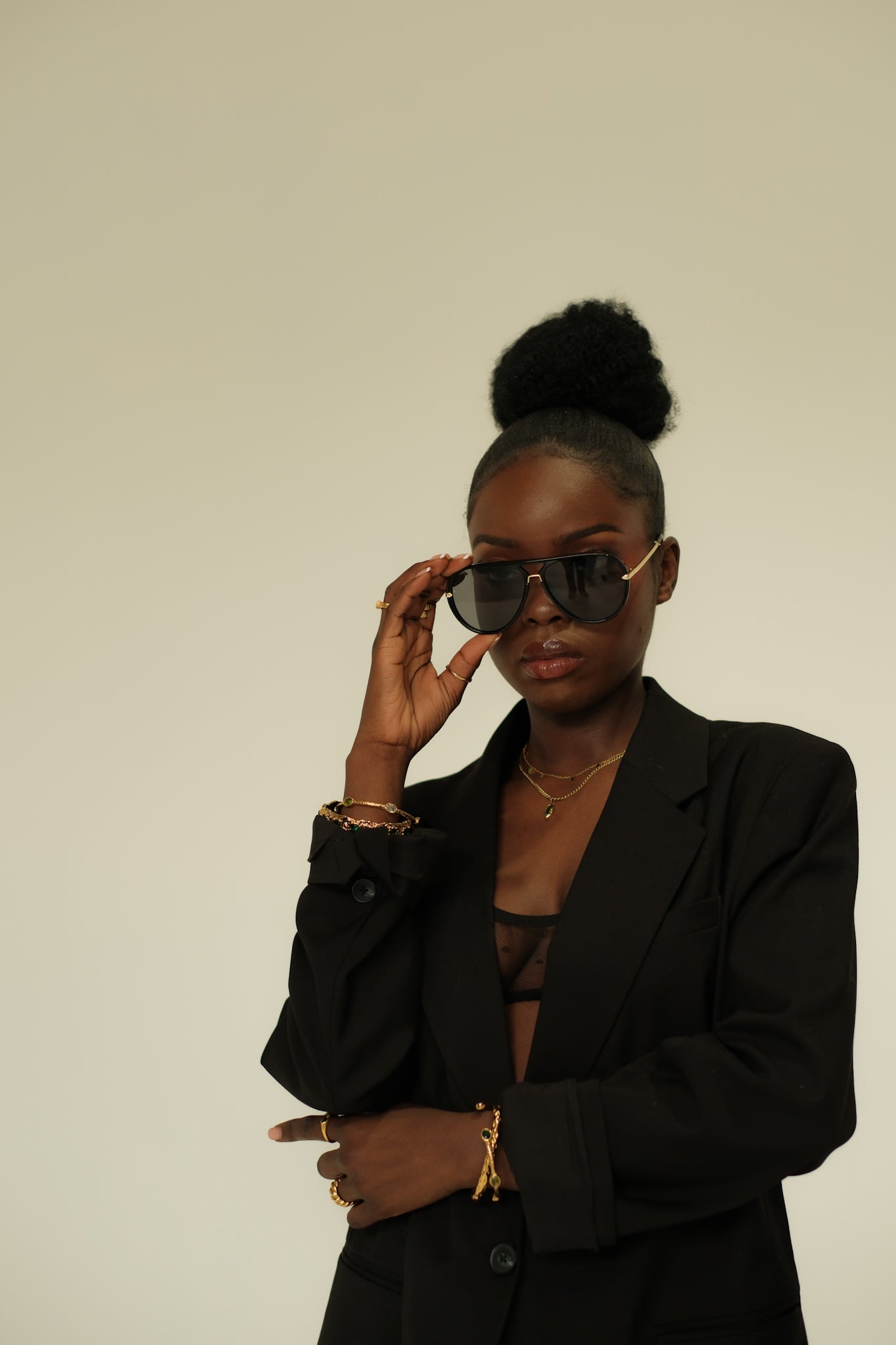Woman wearing sunglasses and a black blazer against a plain background