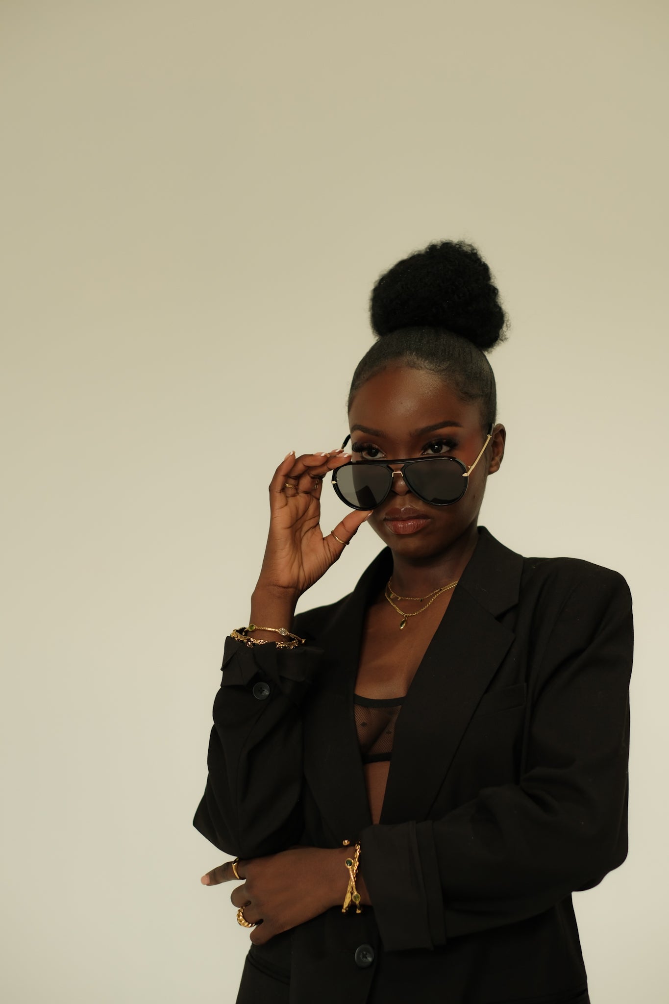 Woman wearing a black blazer and sunglasses against a plain background