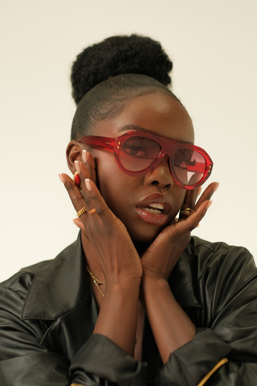 Person wearing red sunglasses and a black leather jacket against a plain background
