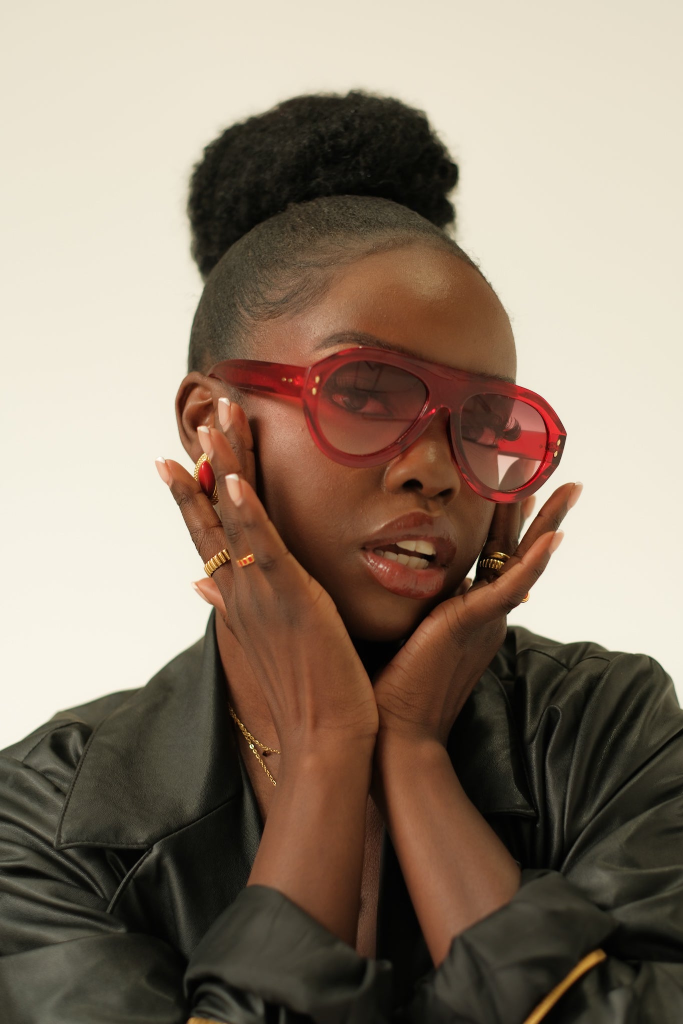 Person wearing red sunglasses and a black leather jacket against a plain background